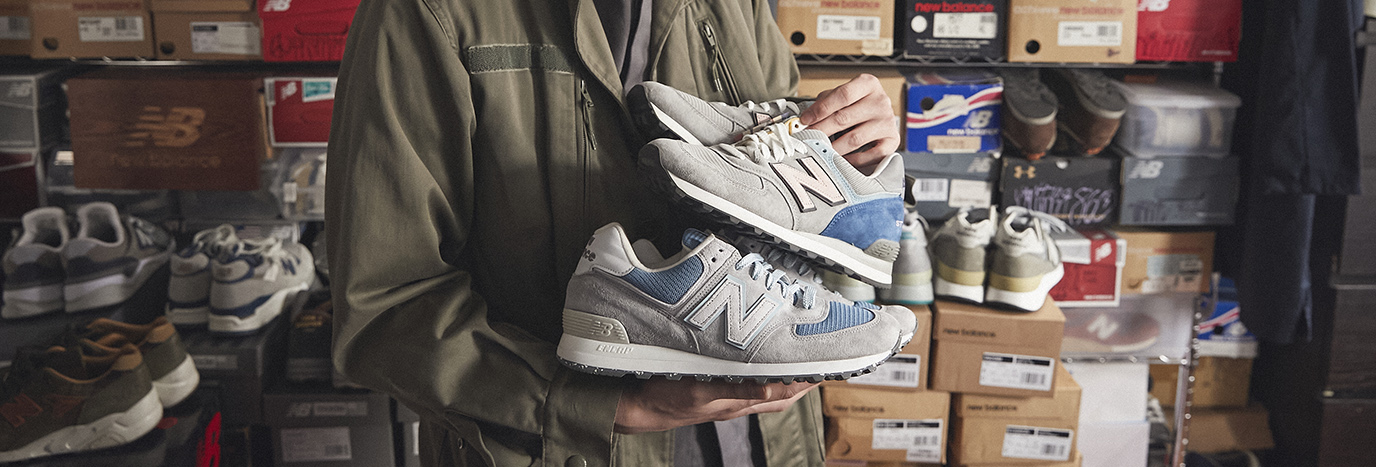 A person holding grey and blue new balance 574's